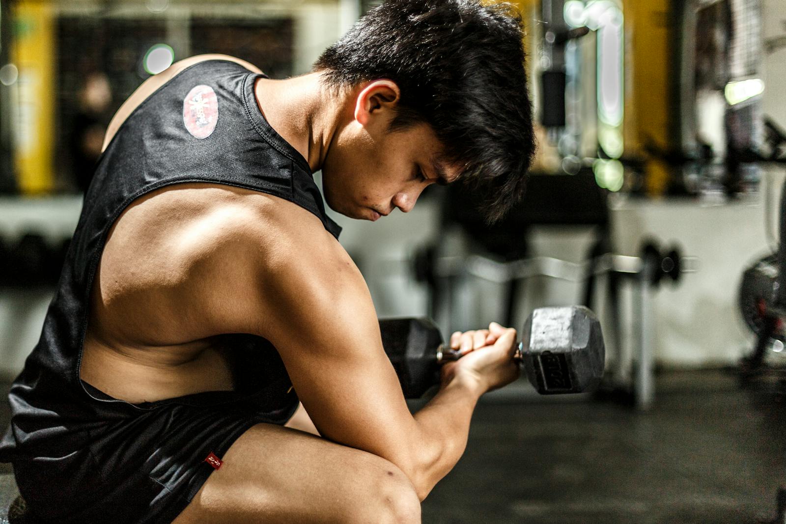 Young man intensely lifting a dumbbell in a gym, highlighting strength and focus.