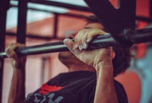 Focused shot of a man doing pull-ups in a gym, highlighting his strength and endurance.