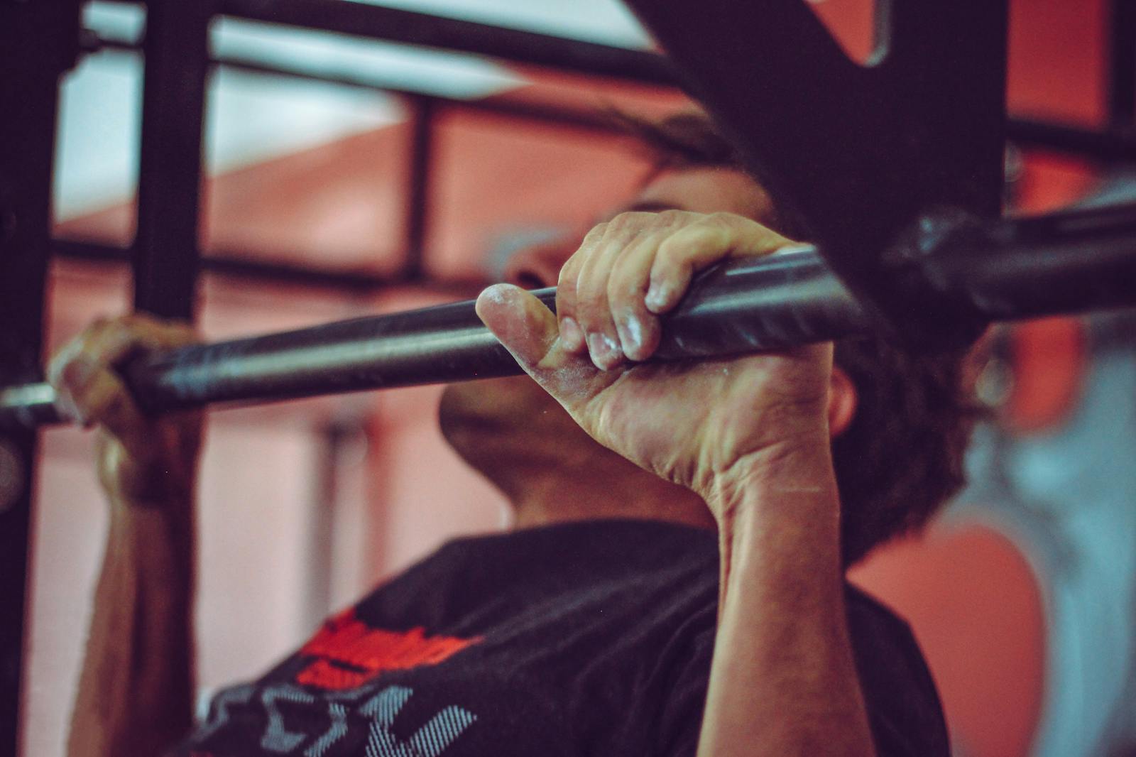 Focused shot of a man doing pull-ups in a gym, highlighting his strength and endurance.