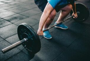 A man deadlifting a barbell indoors showcasing power, fitness, and dedication.